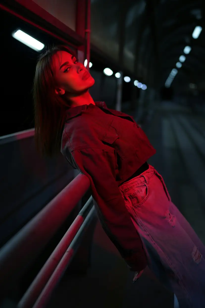 Woman leaning back on a railing in red-magenta neon light at night